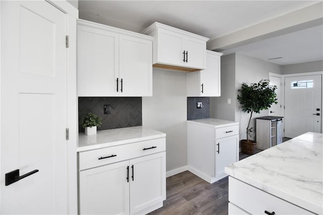 kitchen featuring backsplash, white cabinetry, hardwood / wood-style floors, and light stone counters