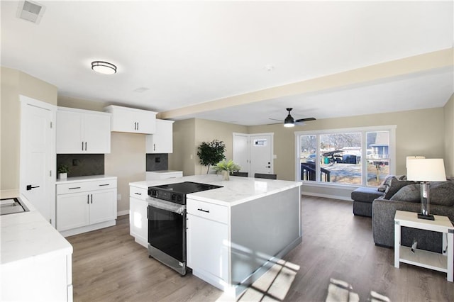 kitchen with white cabinets, a center island, and stainless steel range with electric cooktop