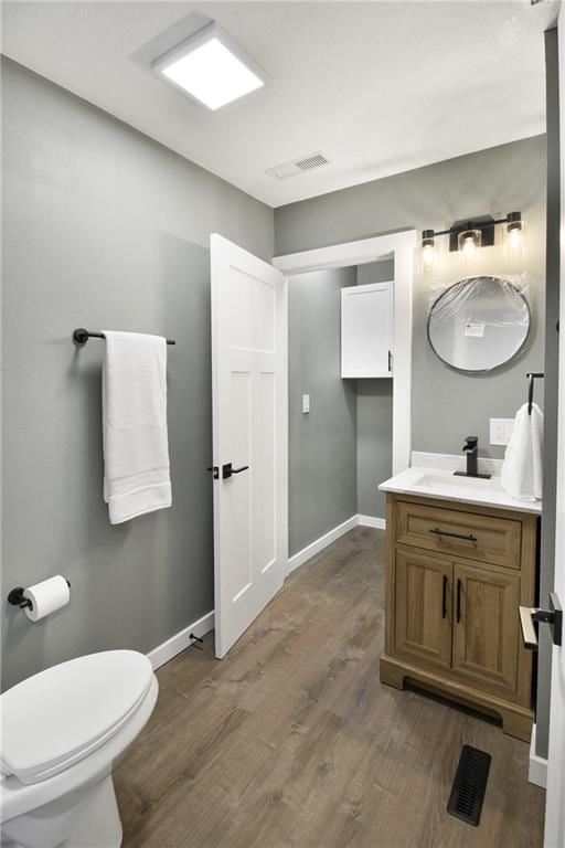 bathroom with hardwood / wood-style floors, vanity, and toilet