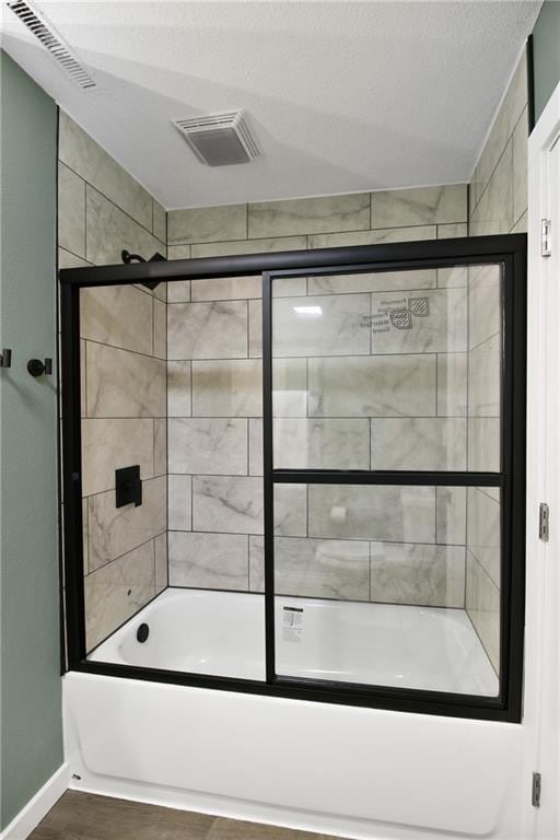 bathroom with enclosed tub / shower combo and a textured ceiling