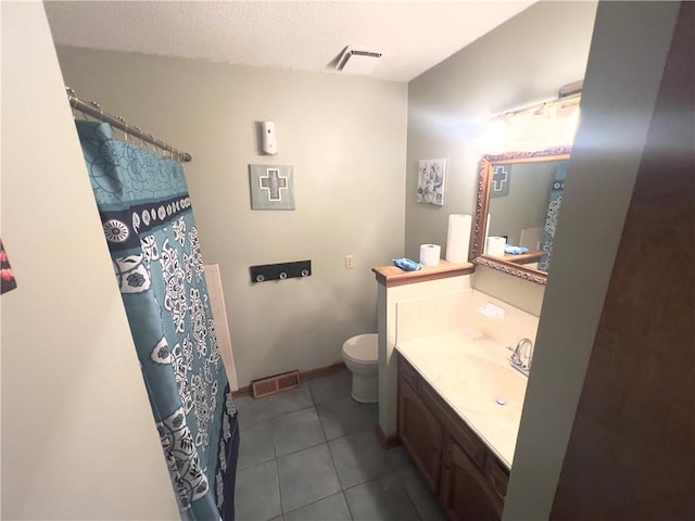 bathroom with a textured ceiling, tile patterned flooring, vanity, and toilet