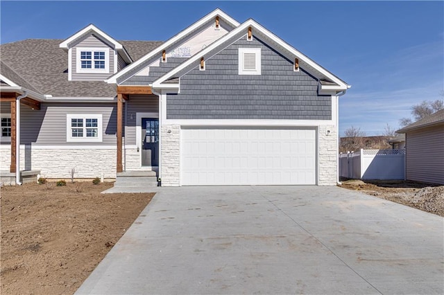 view of front facade featuring an attached garage, a shingled roof, fence, driveway, and stone siding