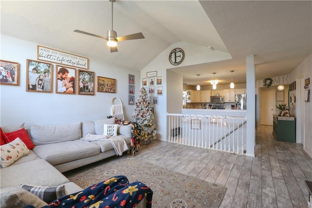 living room with hardwood / wood-style flooring, ceiling fan, and lofted ceiling