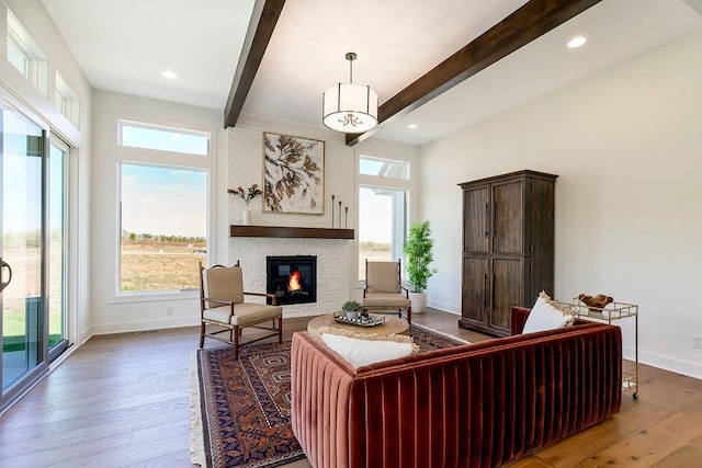 living room featuring beam ceiling, a large fireplace, and hardwood / wood-style flooring