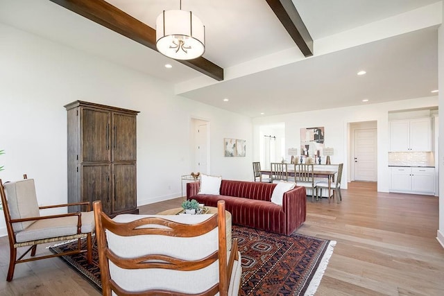 living room with beamed ceiling, a notable chandelier, and light hardwood / wood-style flooring