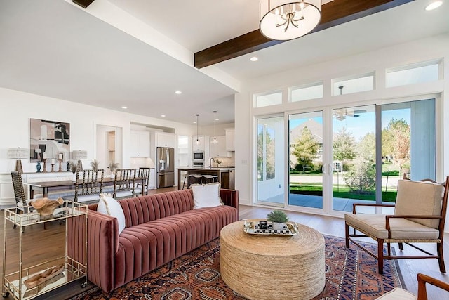 living room featuring beam ceiling, dark hardwood / wood-style flooring, sink, and an inviting chandelier