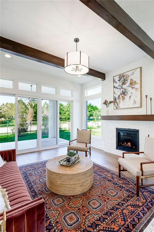 living room with hardwood / wood-style floors, beam ceiling, and a fireplace