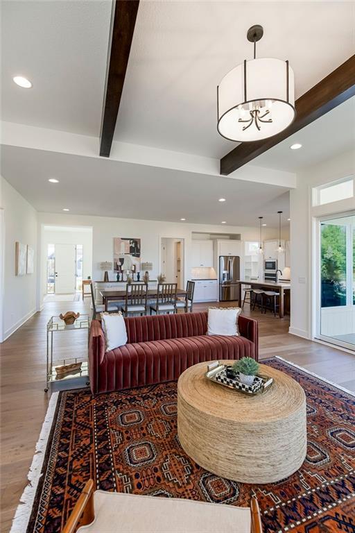 living room with beamed ceiling, hardwood / wood-style flooring, and an inviting chandelier