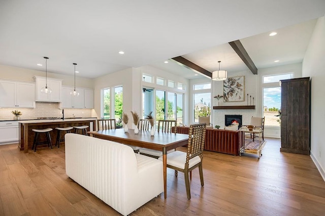 dining room with beam ceiling, light wood-type flooring, and a wealth of natural light