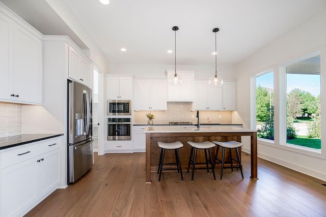 kitchen featuring appliances with stainless steel finishes, dark hardwood / wood-style flooring, decorative light fixtures, and white cabinetry