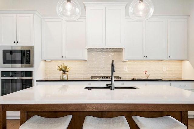 kitchen featuring built in microwave, an island with sink, oven, a kitchen bar, and decorative backsplash