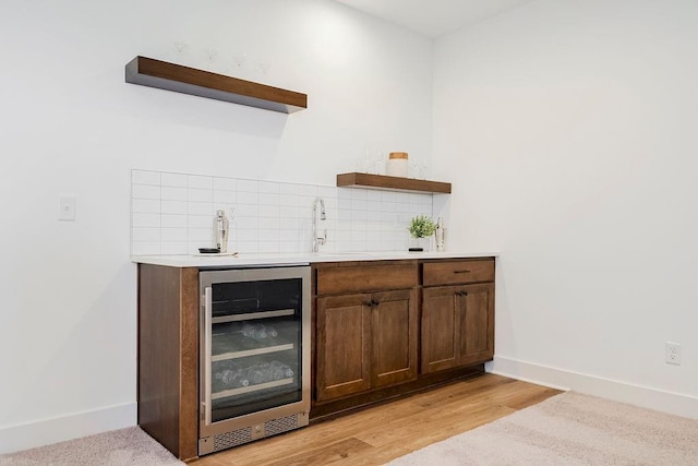 bar with light hardwood / wood-style floors, sink, wine cooler, and tasteful backsplash