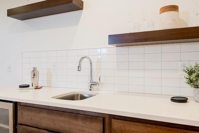 kitchen featuring decorative backsplash, sink, and beverage cooler