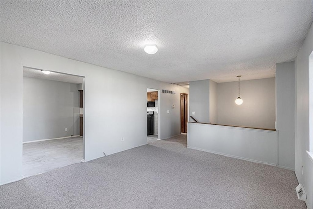 carpeted empty room featuring a textured ceiling