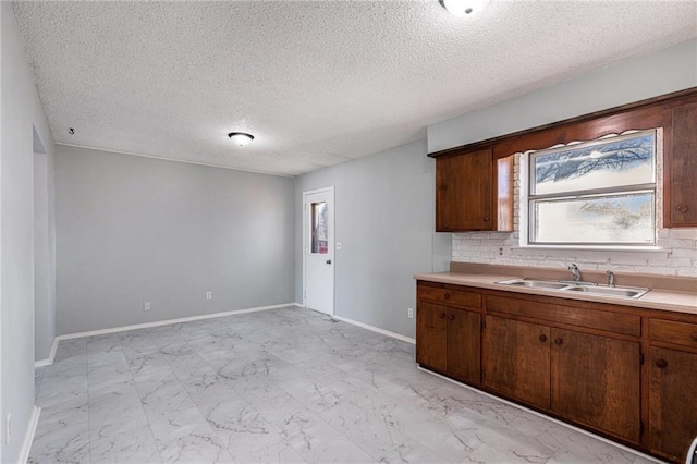 kitchen with backsplash, sink, and a textured ceiling