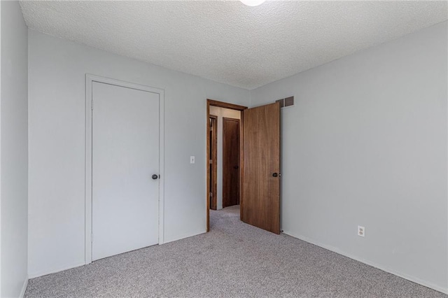 unfurnished bedroom featuring a closet, light colored carpet, and a textured ceiling