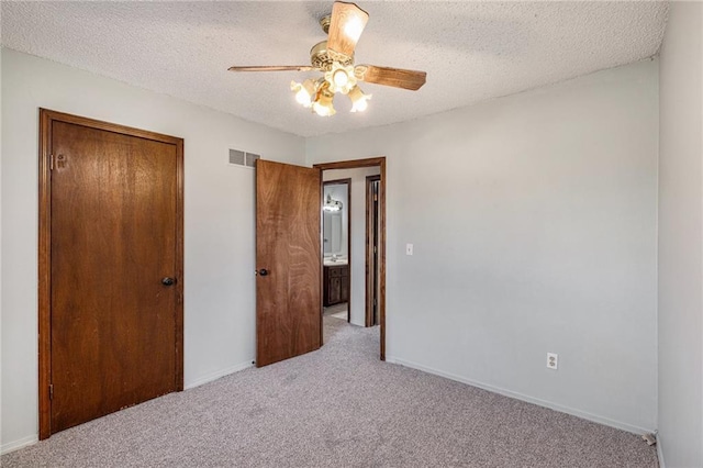 unfurnished bedroom featuring a textured ceiling, light colored carpet, and ceiling fan