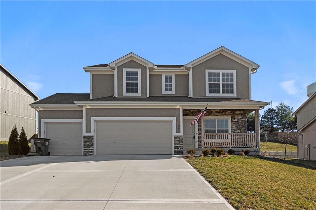 view of front of home featuring covered porch, a garage, and a front lawn