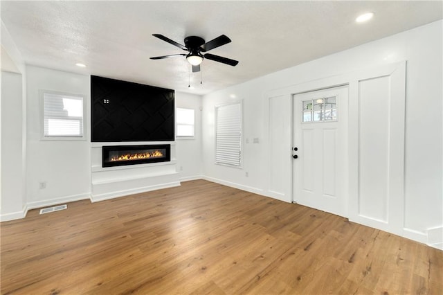 entryway featuring a fireplace, ceiling fan, and light hardwood / wood-style flooring