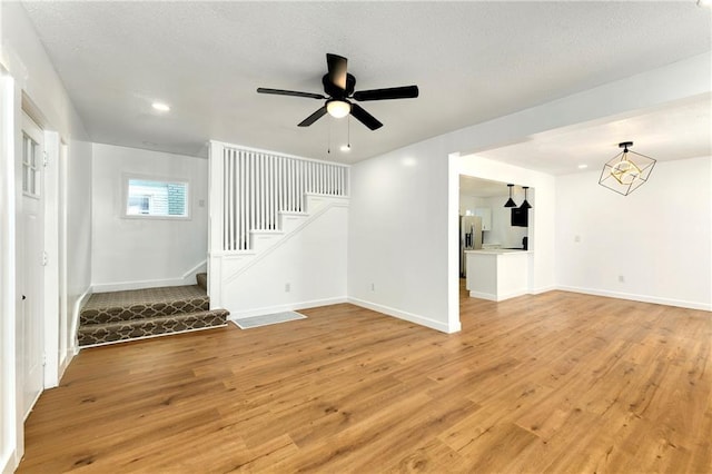 unfurnished living room featuring ceiling fan and light wood-type flooring