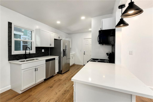 kitchen featuring sink, pendant lighting, kitchen peninsula, and appliances with stainless steel finishes