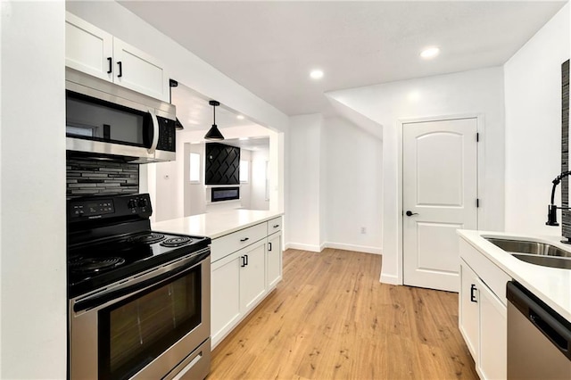 kitchen with light hardwood / wood-style floors, stainless steel appliances, decorative backsplash, white cabinetry, and decorative light fixtures