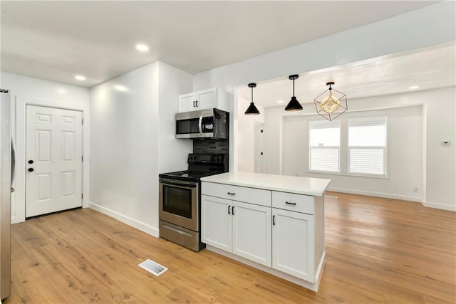 kitchen featuring appliances with stainless steel finishes, light hardwood / wood-style floors, pendant lighting, white cabinetry, and tasteful backsplash