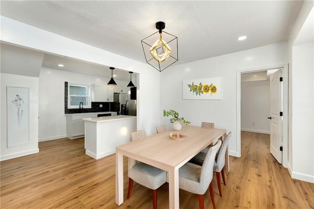 dining area with sink and light wood-type flooring