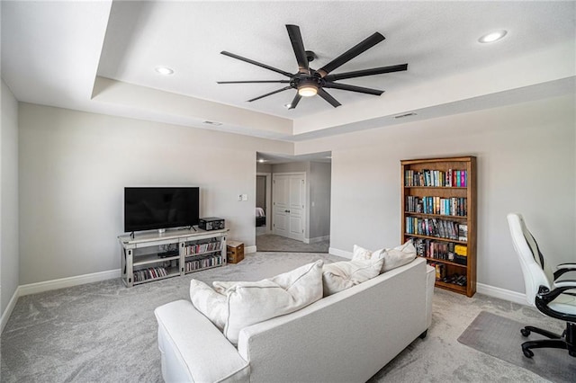 living room featuring light carpet, ceiling fan, and a tray ceiling