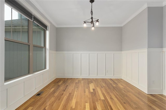 empty room featuring light hardwood / wood-style floors, ornamental molding, and an inviting chandelier