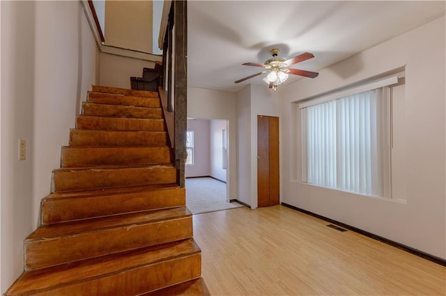 stairway with hardwood / wood-style flooring and ceiling fan