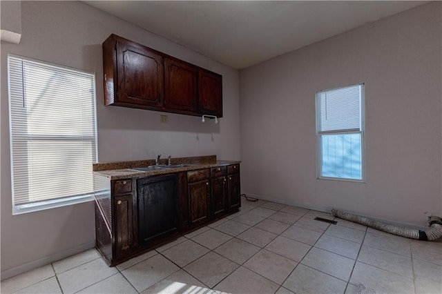 kitchen with light tile patterned flooring, dark brown cabinetry, and sink