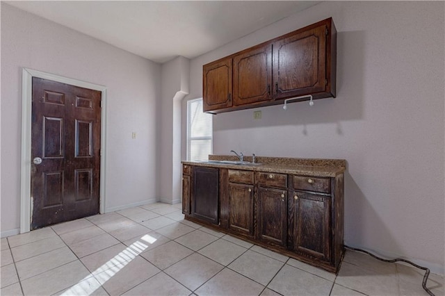 kitchen featuring light tile patterned floors, dark brown cabinetry, and sink