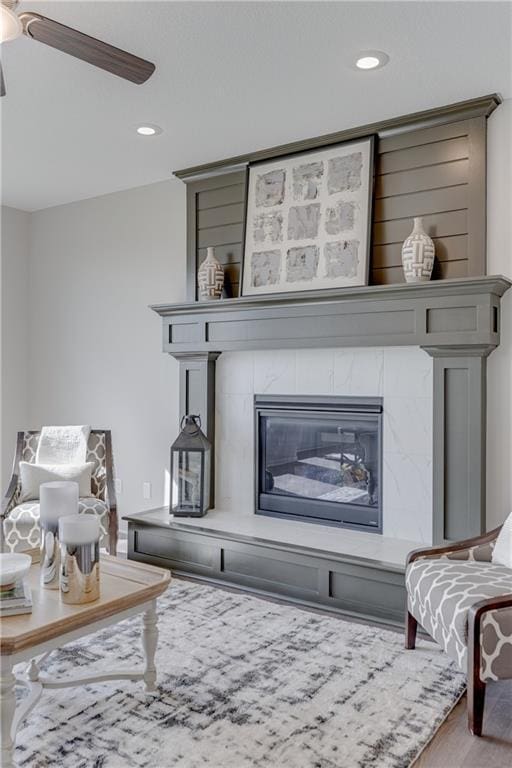 sitting room featuring hardwood / wood-style flooring, ceiling fan, and a tiled fireplace