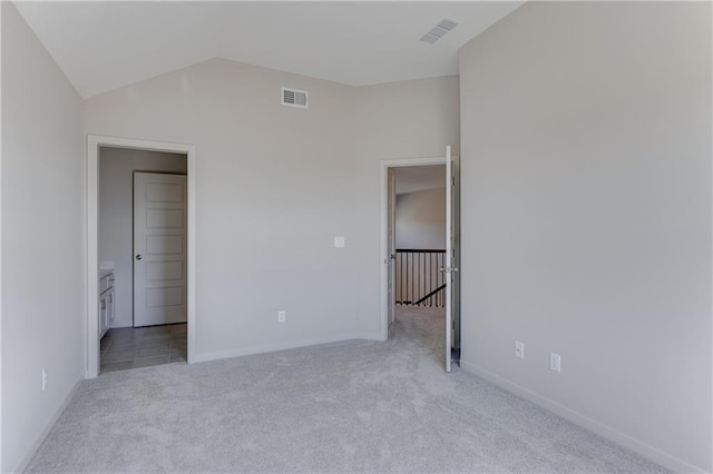 unfurnished bedroom with light colored carpet and vaulted ceiling