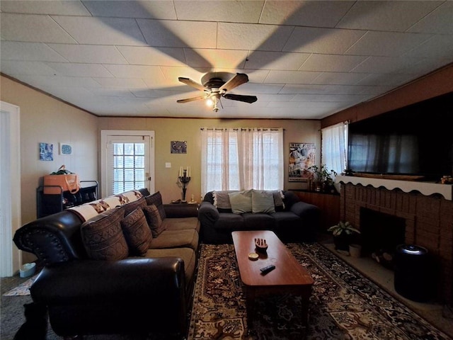 carpeted living room with ceiling fan and a brick fireplace