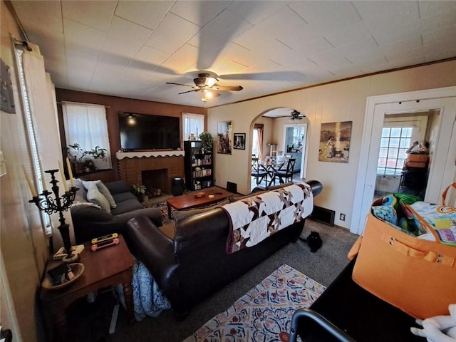 living room with carpet flooring, a brick fireplace, ceiling fan, and ornamental molding