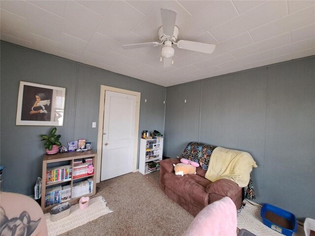 sitting room with ceiling fan and carpet