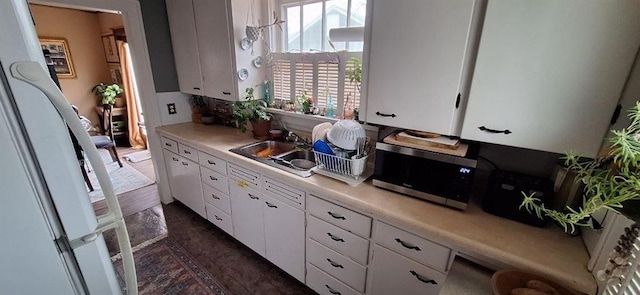 kitchen featuring white cabinets, white refrigerator, and sink