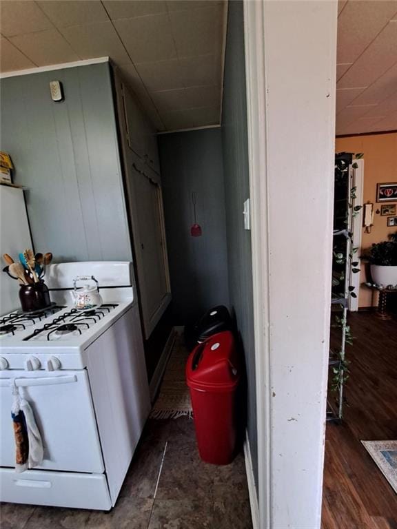 kitchen featuring white gas range and wood walls