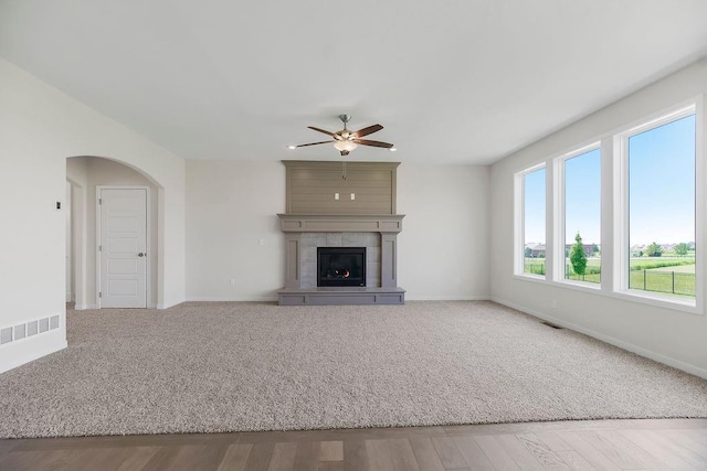 17157 W 164th Ter, Olathe, KS 66062 - unfurnished living room featuring a ceiling fan, a fireplace, arched walkways, and wood finished floors