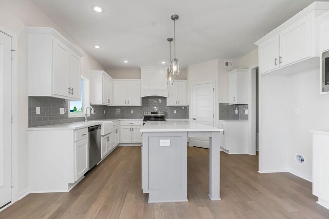 17157 W 164th Ter, Olathe, KS 66062 - kitchen featuring stainless steel appliances, wood finished floors, backsplash, a center island, and white cabinetry