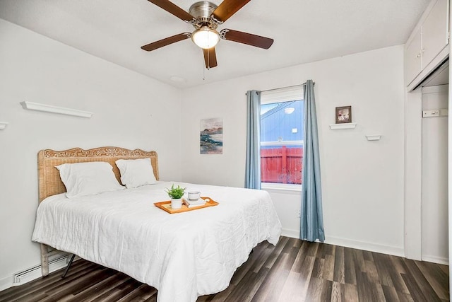 bedroom featuring ceiling fan, dark hardwood / wood-style floors, baseboard heating, and a closet