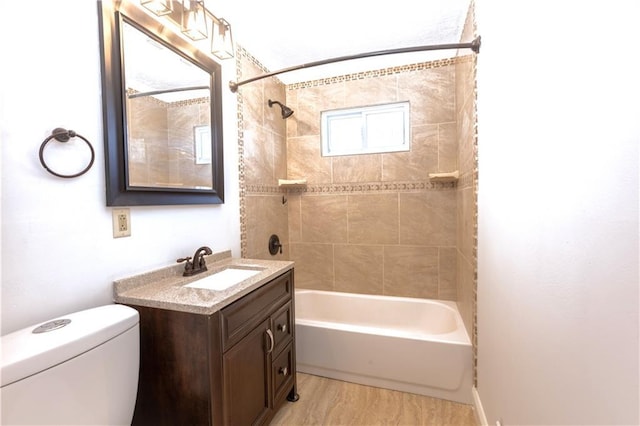 full bathroom featuring tiled shower / bath combo, toilet, and vanity