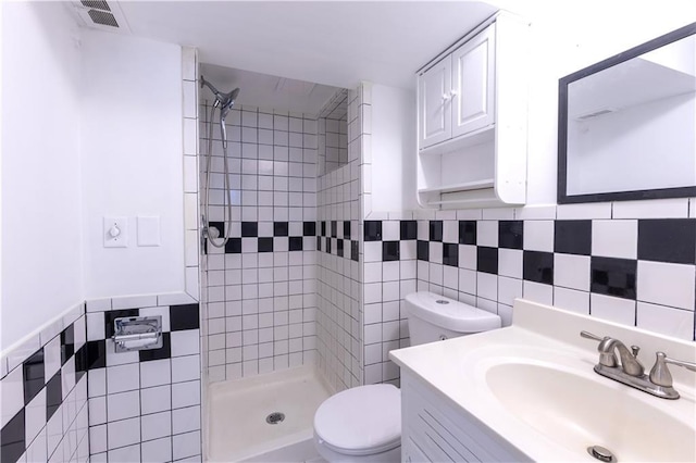 bathroom featuring tiled shower, toilet, and tile walls