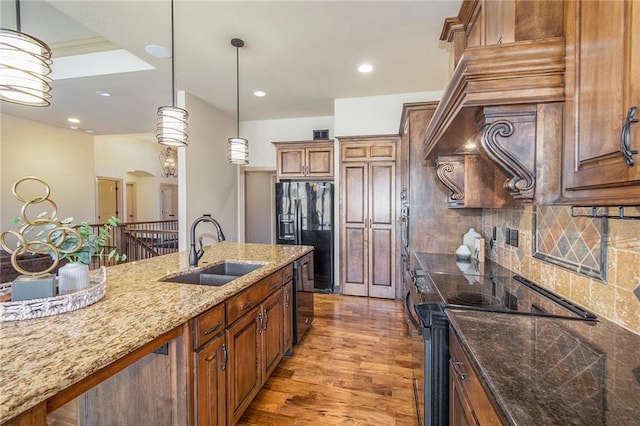 kitchen featuring range with electric stovetop, hardwood / wood-style floors, pendant lighting, sink, and dark stone counters