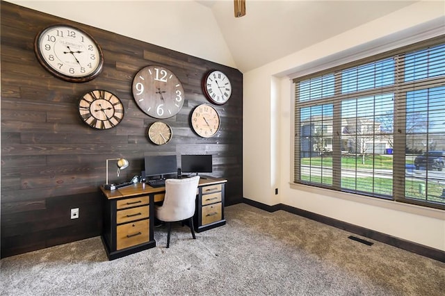 carpeted office with lofted ceiling and wood walls