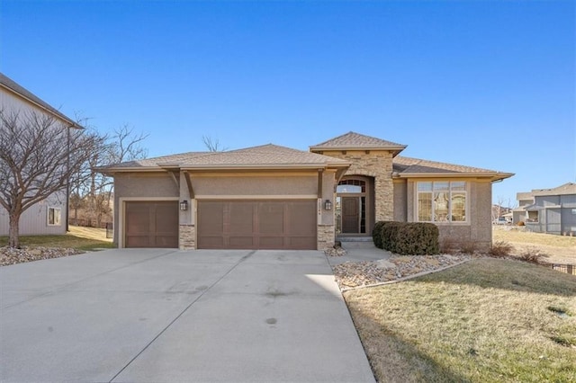 prairie-style house featuring a garage, concrete driveway, stone siding, and stucco siding