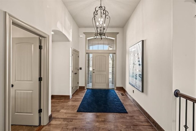 entrance foyer with dark wood-style floors, a chandelier, visible vents, and baseboards