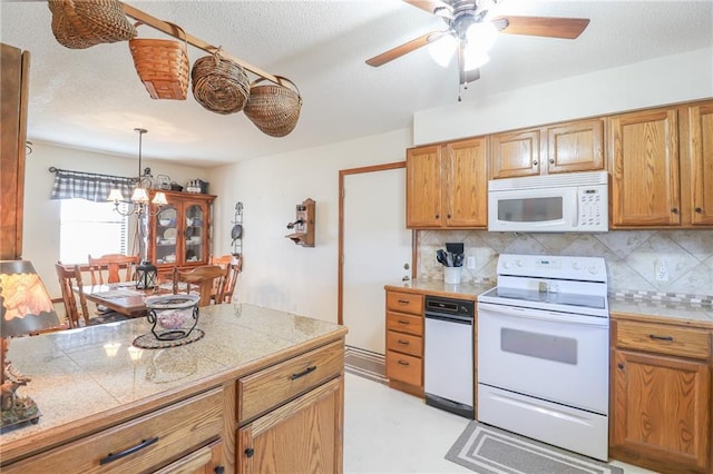 kitchen featuring pendant lighting, ceiling fan with notable chandelier, white appliances, and backsplash